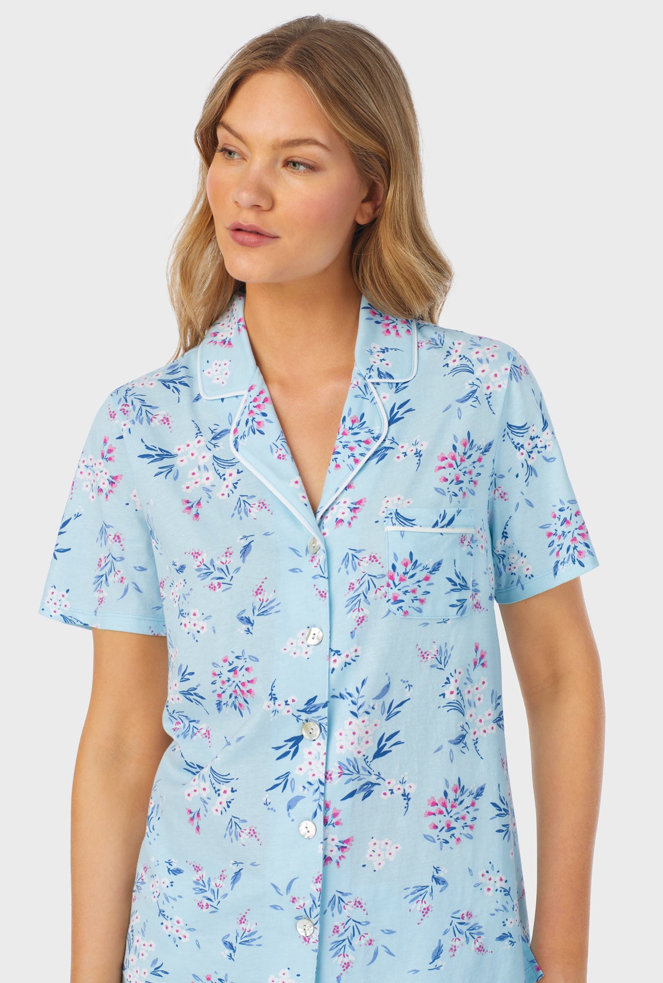 A lady wearing blue short sleeve long pajama set with summer blooms print.