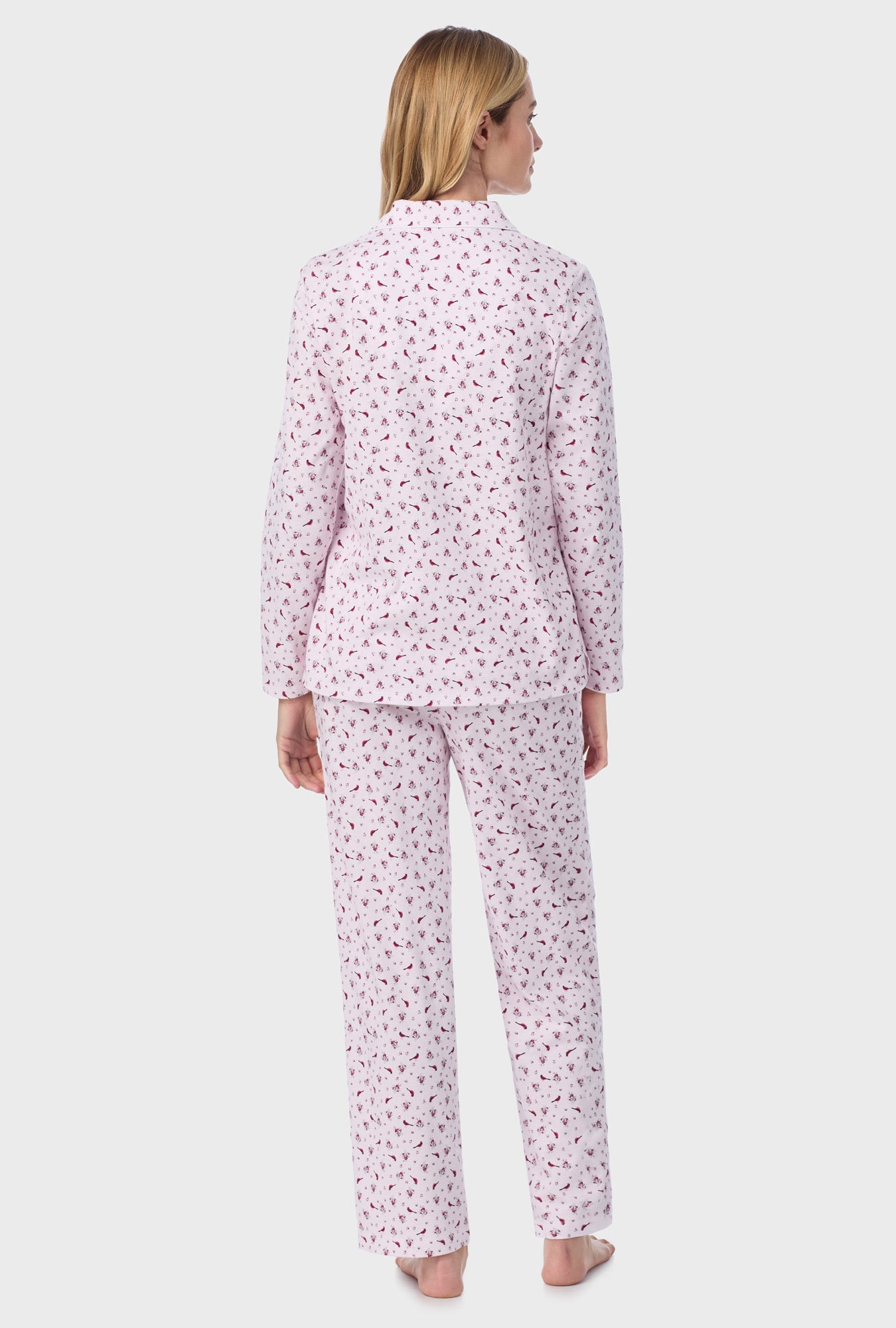 A lady wearing pink long sleeve cotton long pajama set with mini cardinal print.