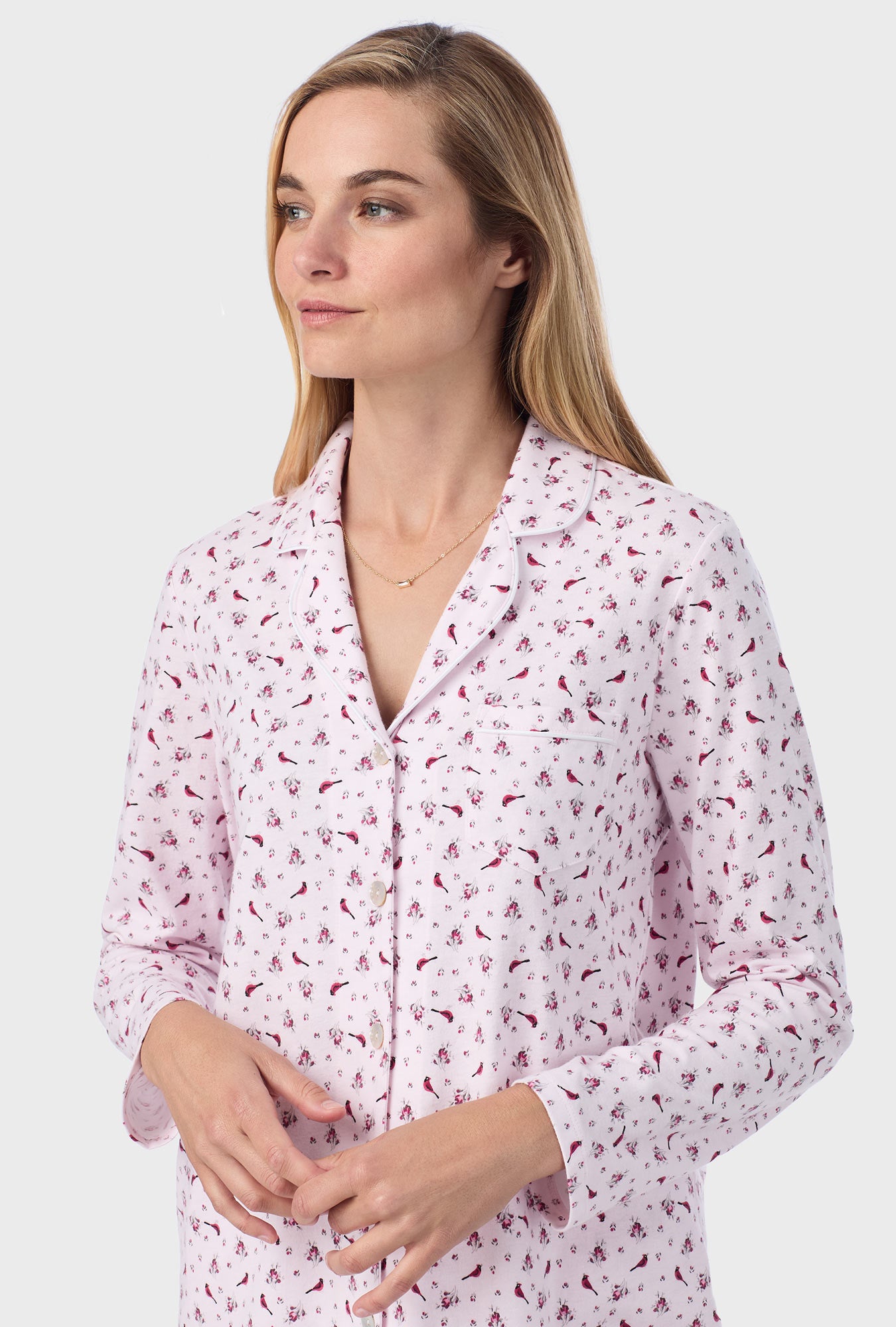 A lady wearing pink long sleeve cotton long pajama set with mini cardinal print.