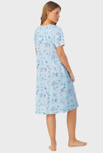 A lady wearing a blue short sleeve waltz nightgown with summer blooms print.
