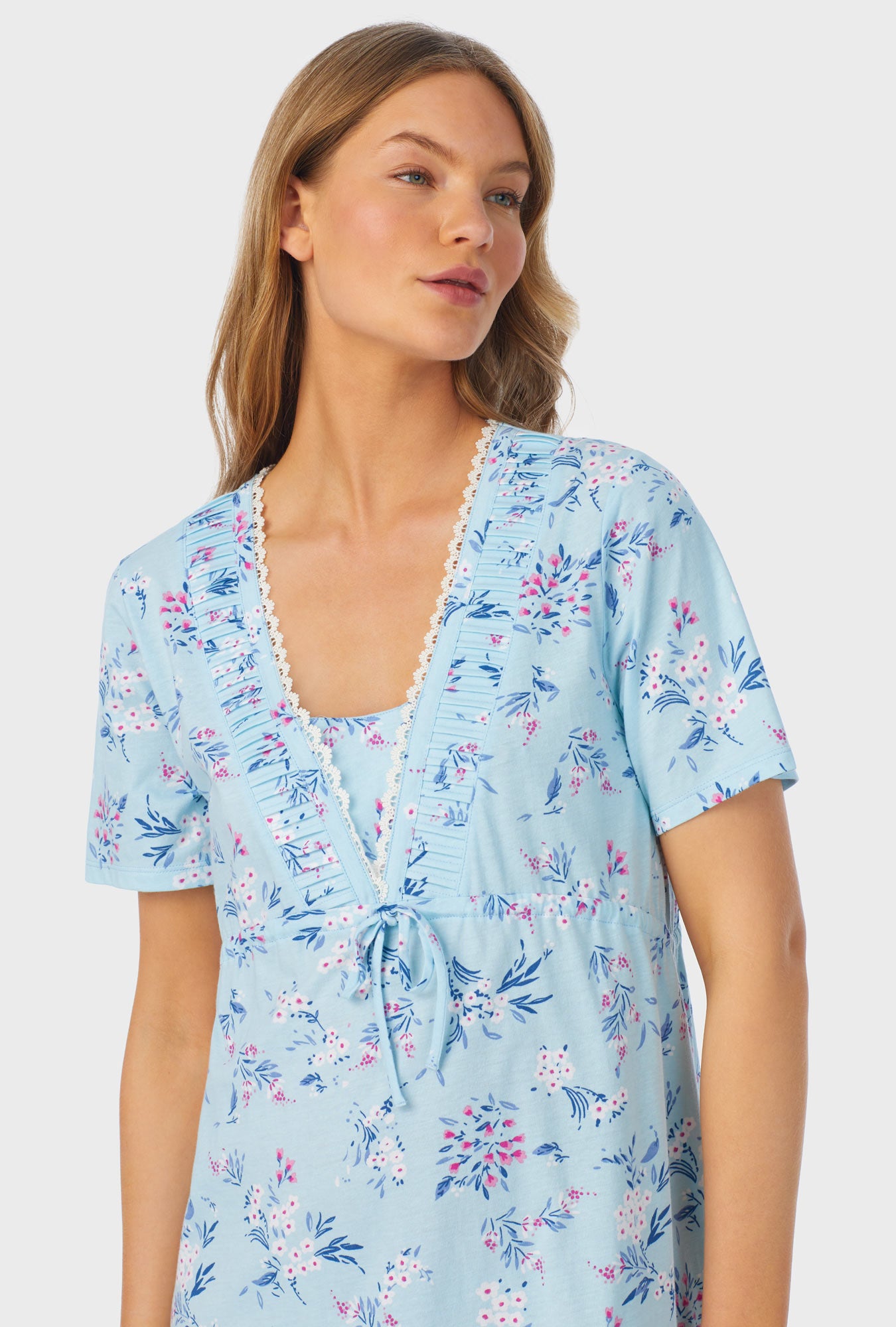 A lady wearing a blue short sleeve waltz nightgown with summer blooms print.