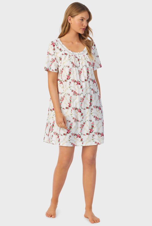 A lady wearing  short sleeve long nightshirt with rose vine print.