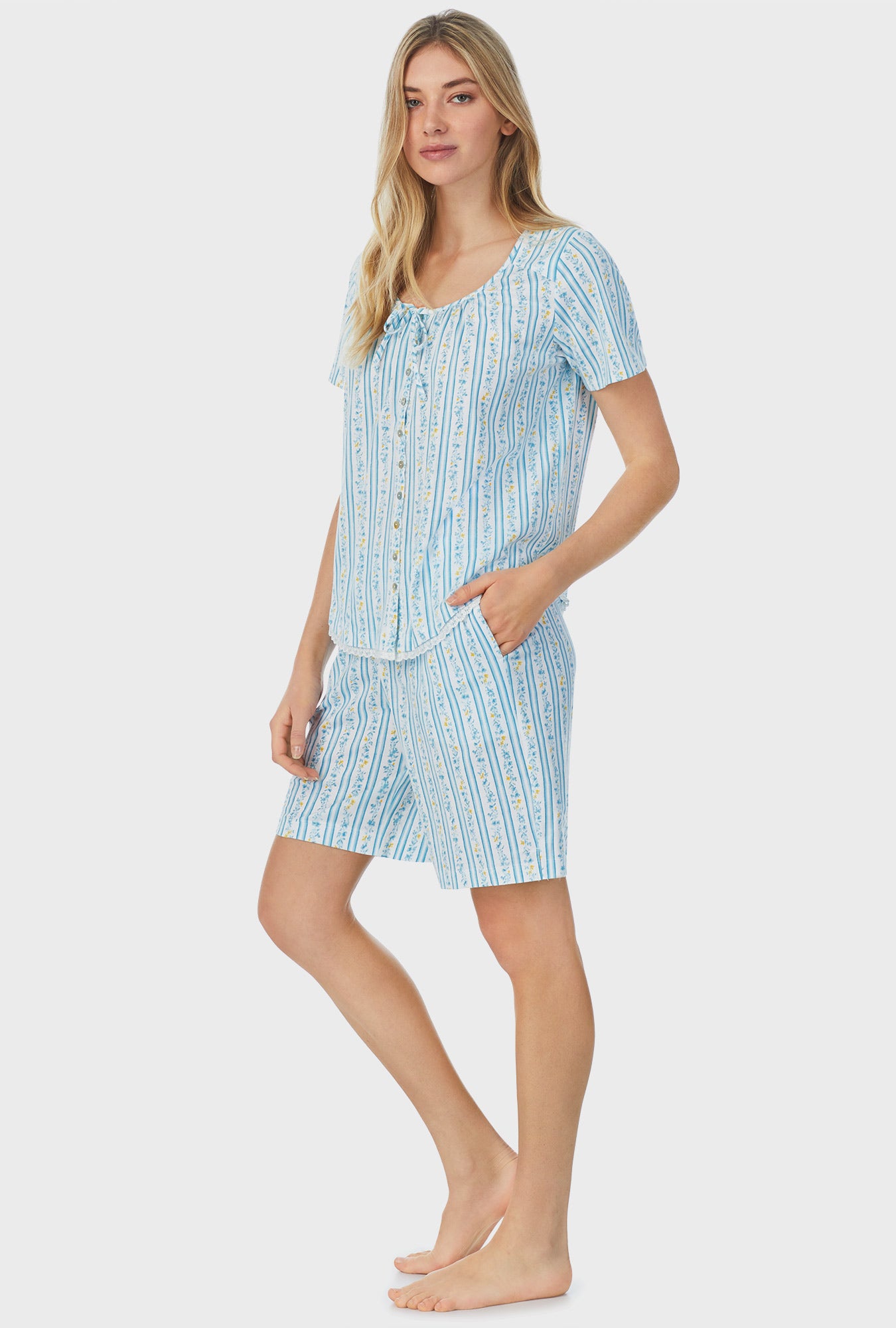 A lady wearing blue short sleeve bermuda pajama set with floral stripes.
