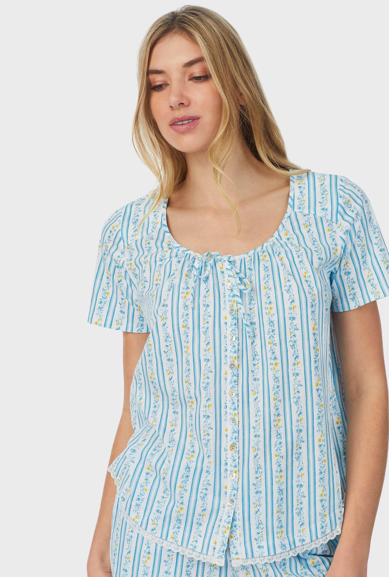 A lady wearing blue short sleeve bermuda pajama set with floral stripes.