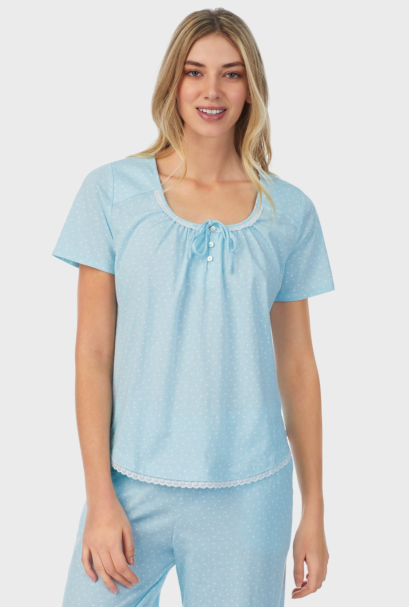 A lady wearing blue short sleeve capri pajama set with aqua dots.