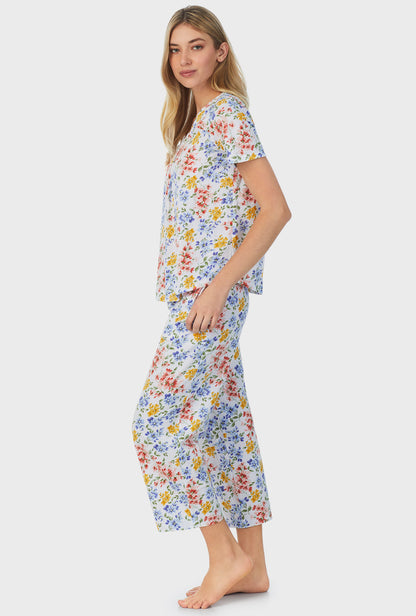 A lady wearing short sleeve capri pajama set with multi floral print.