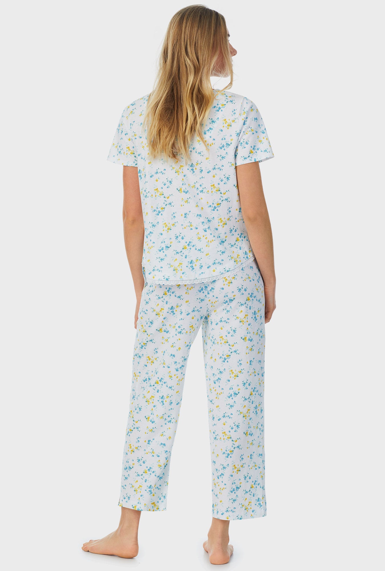 A lady wearing white short sleeve capri pajama set with breeze blooms.