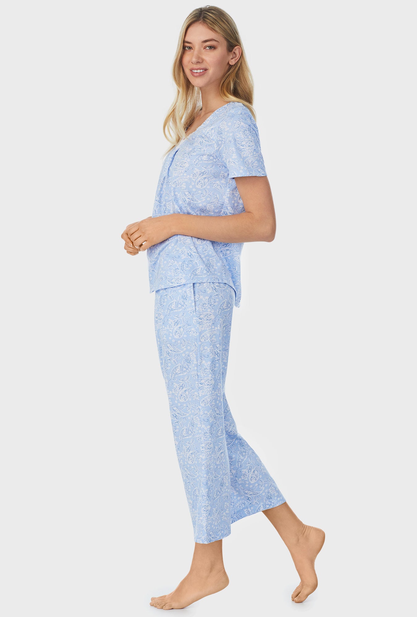 A lady wearing blue short sleeve capri pajama set with blooming paisley print.