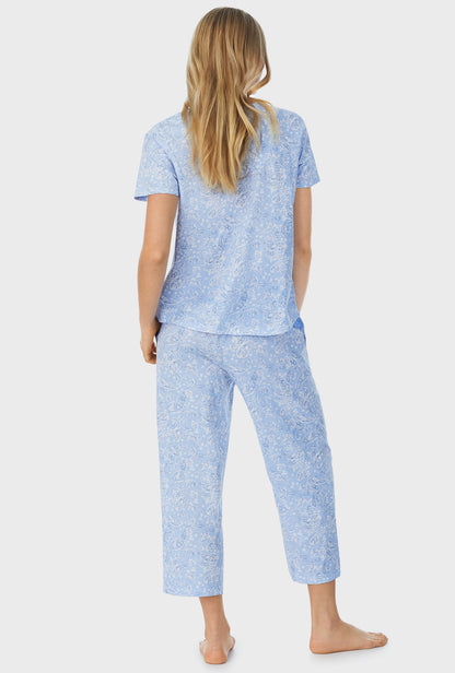 A lady wearing blue short sleeve capri pajama set with blooming paisley print.