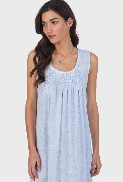 A lady wearing blue sleeveless cotton waltz nightgown with summer magnolia print.