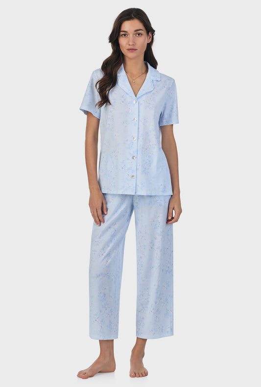 A lady wearing blue short sleeve cotton capri pajama set with summer  magnolia print.