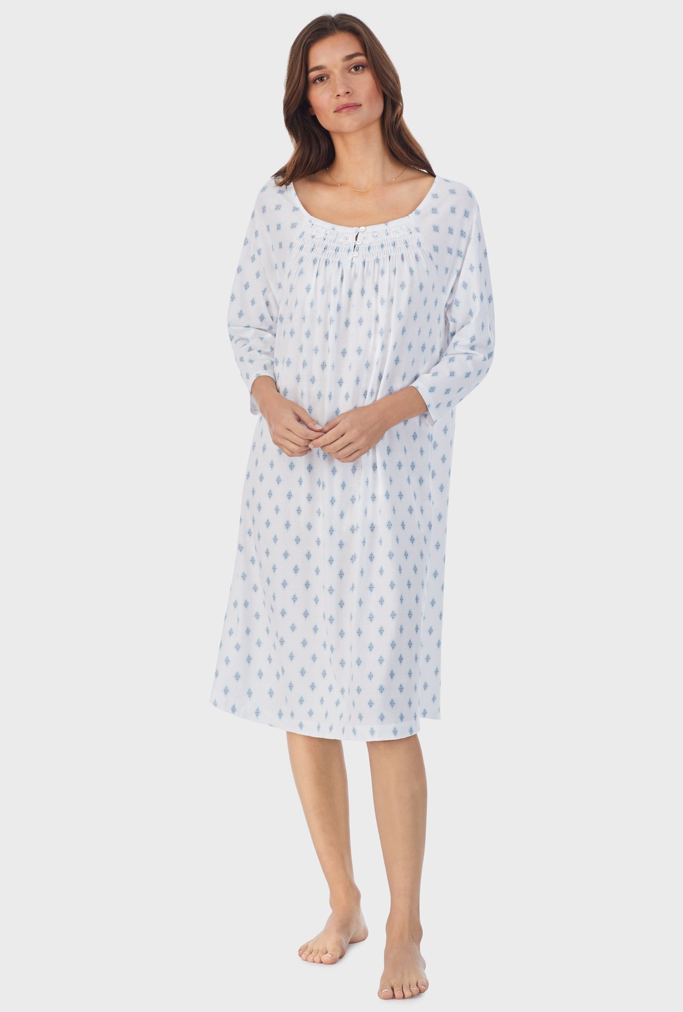 A lady wearing white long sleeve cotton waltz nightgown with aqua geo print. 