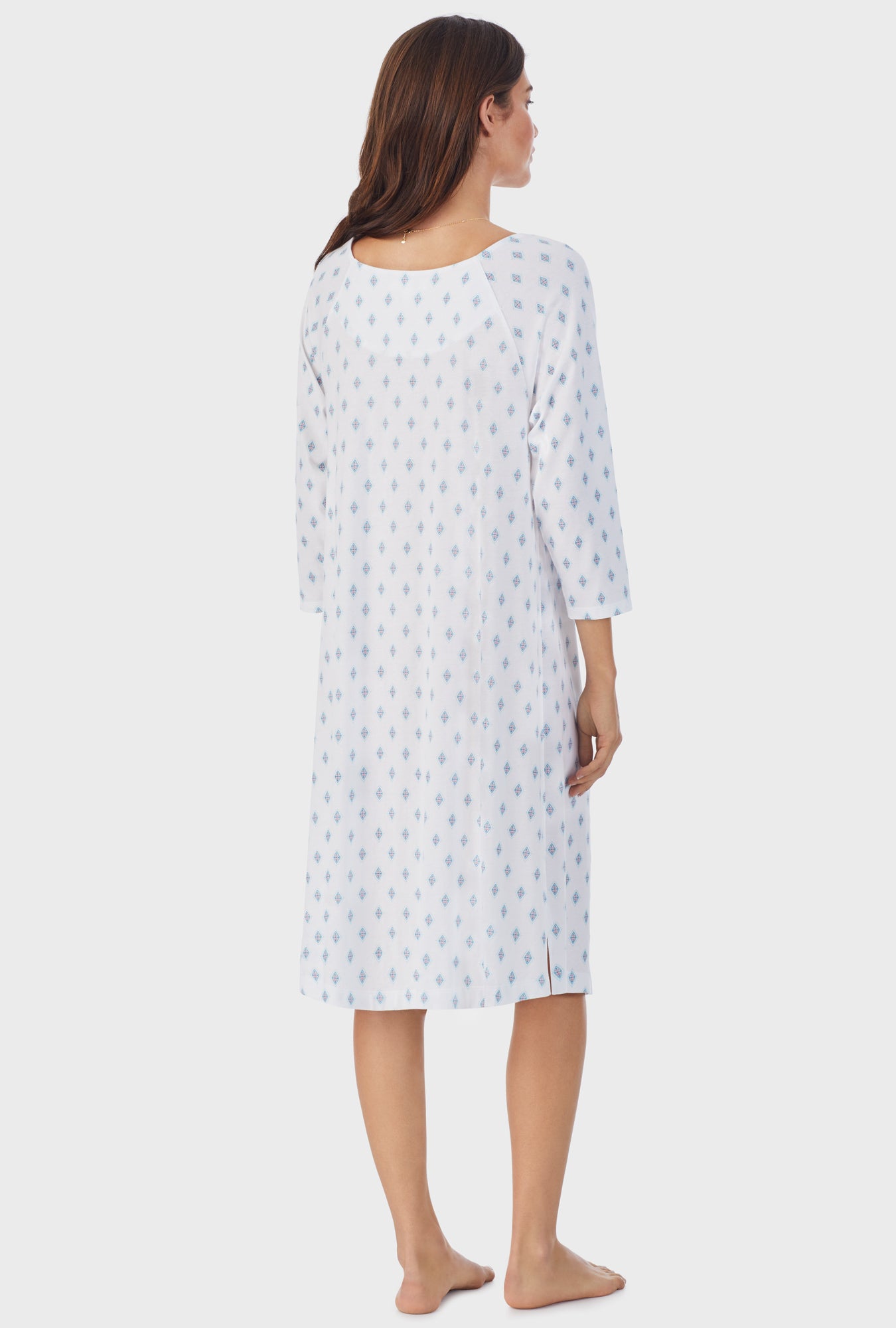  A lady wearing white long sleeve cotton waltz nightgown with aqua geo print. 