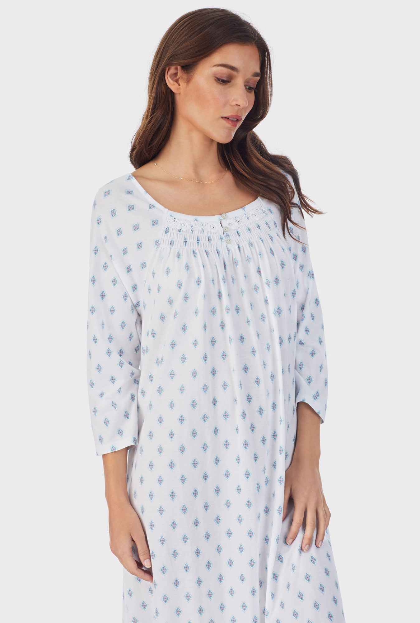  A lady wearing white long sleeve cotton waltz nightgown with aqua geo print. 