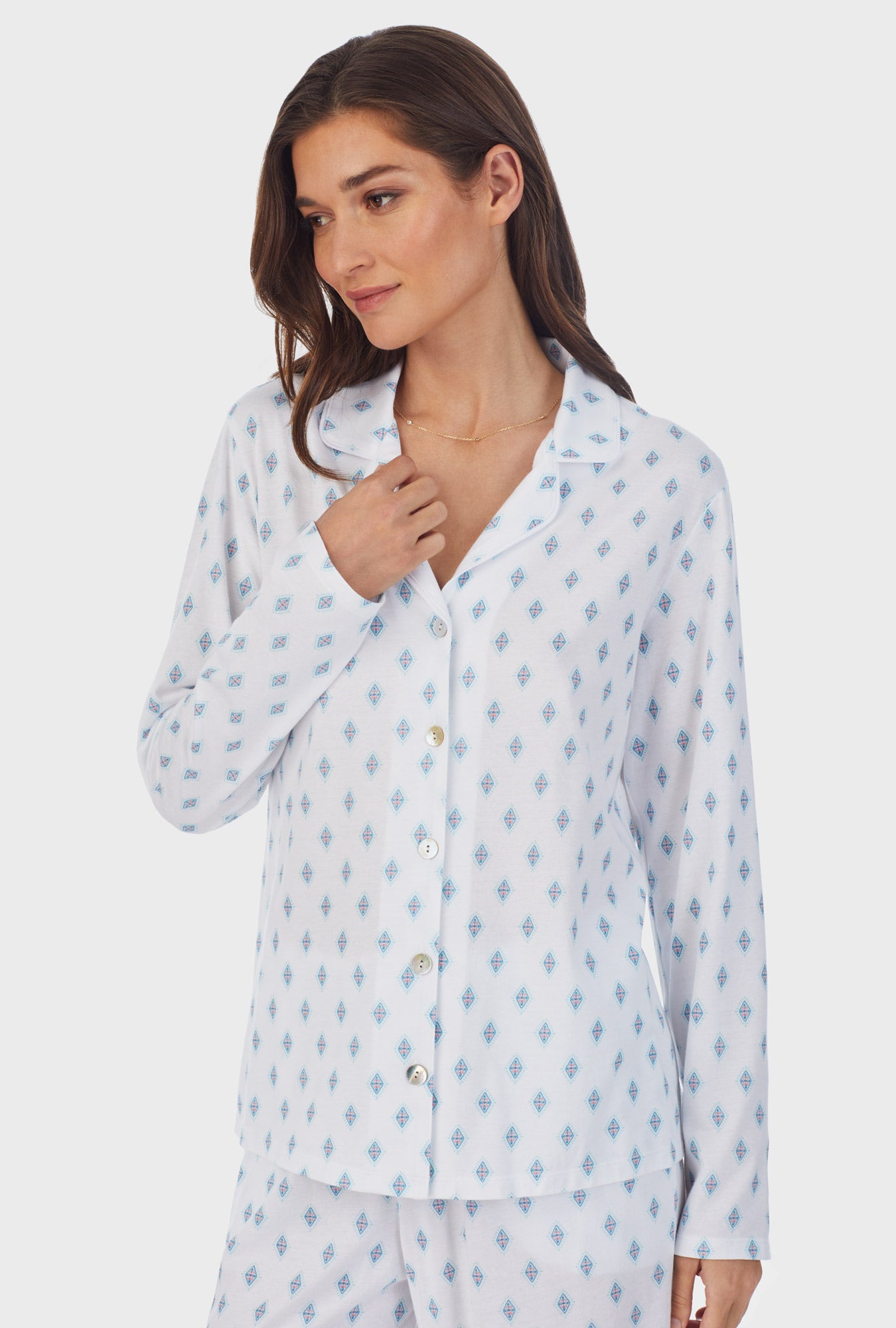 A lady wearing white long pajama set with aqua geo