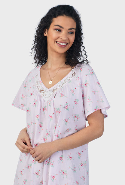 A lady wearing pink short sleeve cotton short plus size nightgown with sweet blooms print.